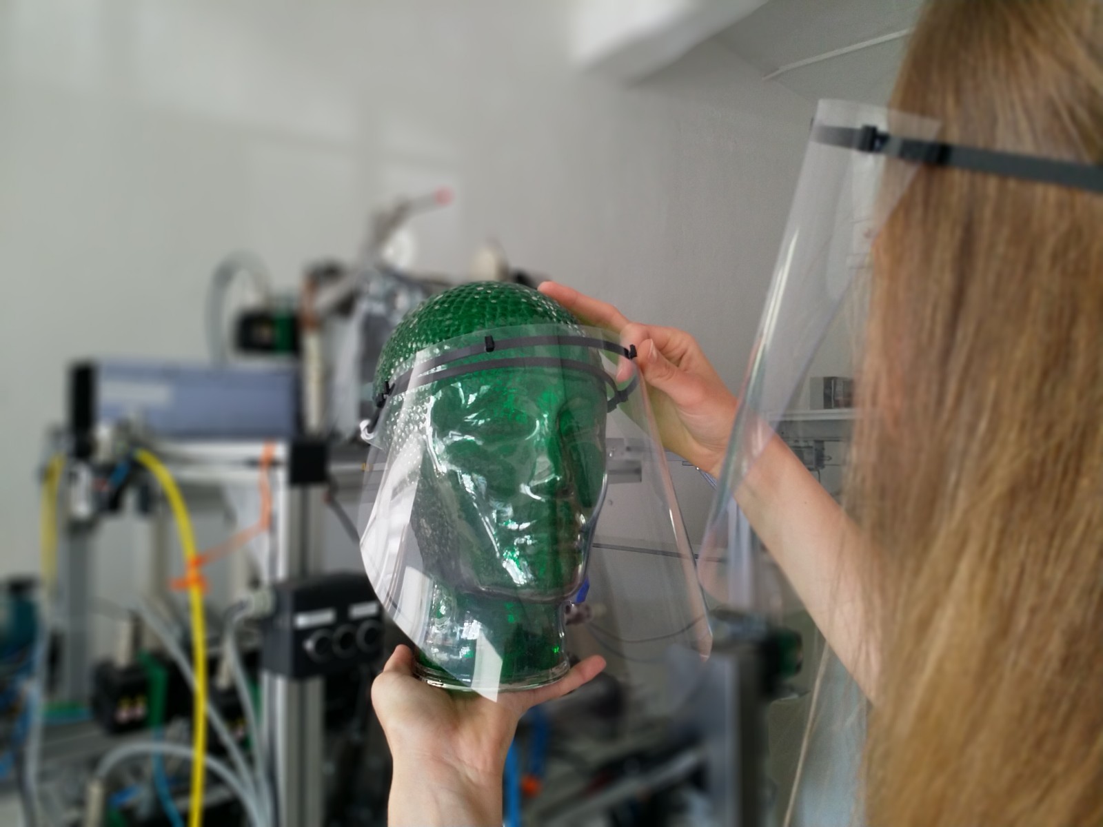 Das Bild zeigt eine Mitarbeiterin des Cetex Institutes mit Gesichtsmasken mit 3D-gedruckten Halterungen